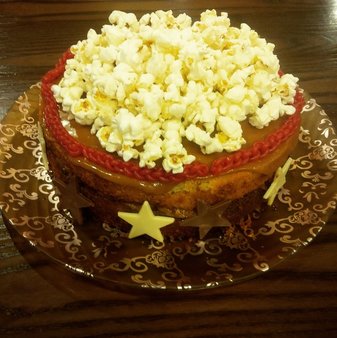 Book Themed Cake - The Night Circus. Caramel cake with a caramelised apple filling, topped with caramel and finished with chocolate stars, edible crocheted strawberry scarves and a popcorn topping. clairewade.com
