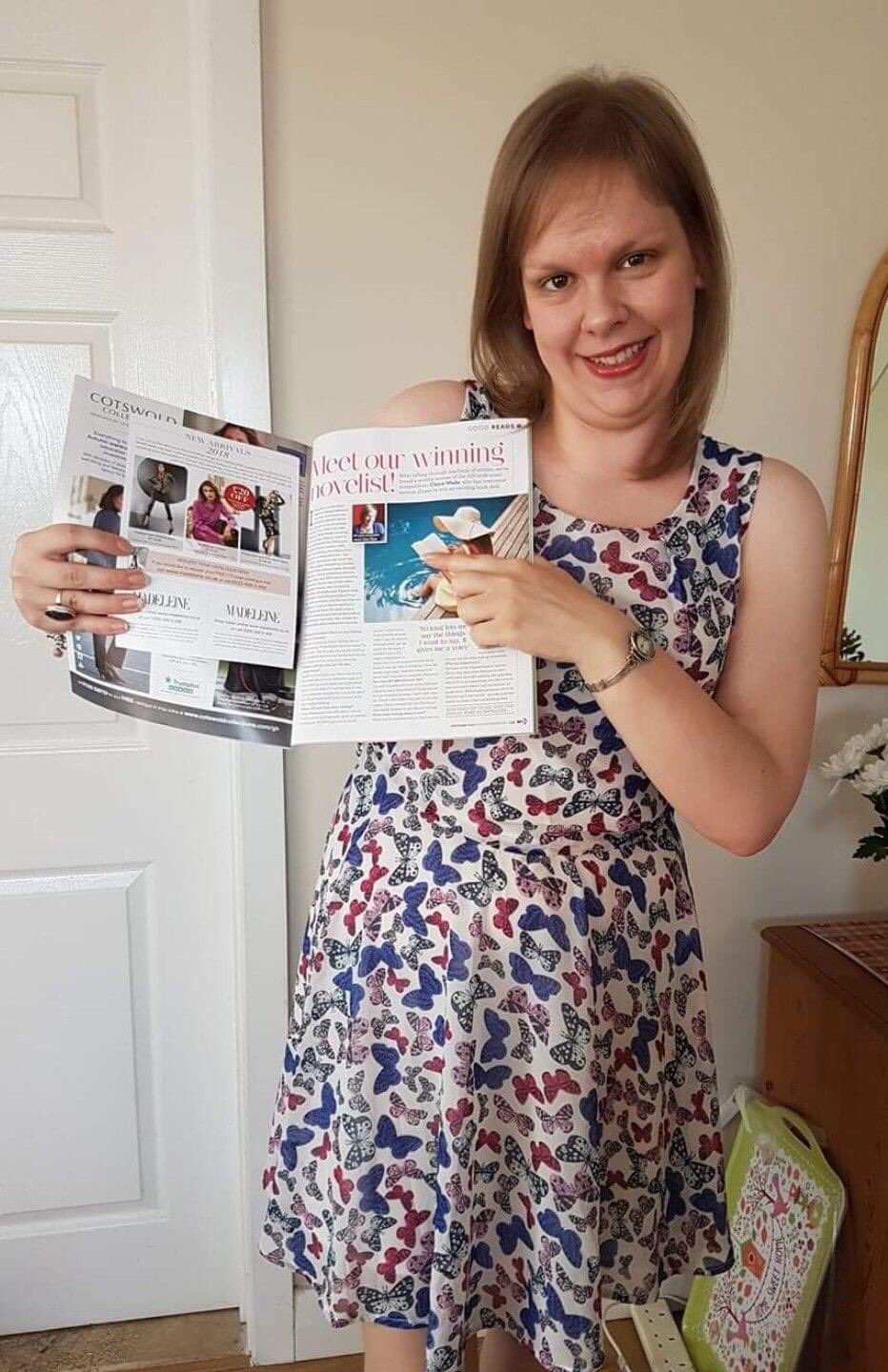 A smiling white woman with blonde hair, holding up a copy of Good Housekeeping magazine.